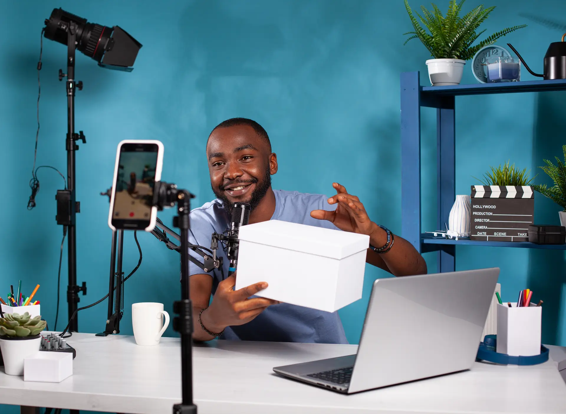 Influencer presenting white mockup gift for fans looking at live video podcast setup